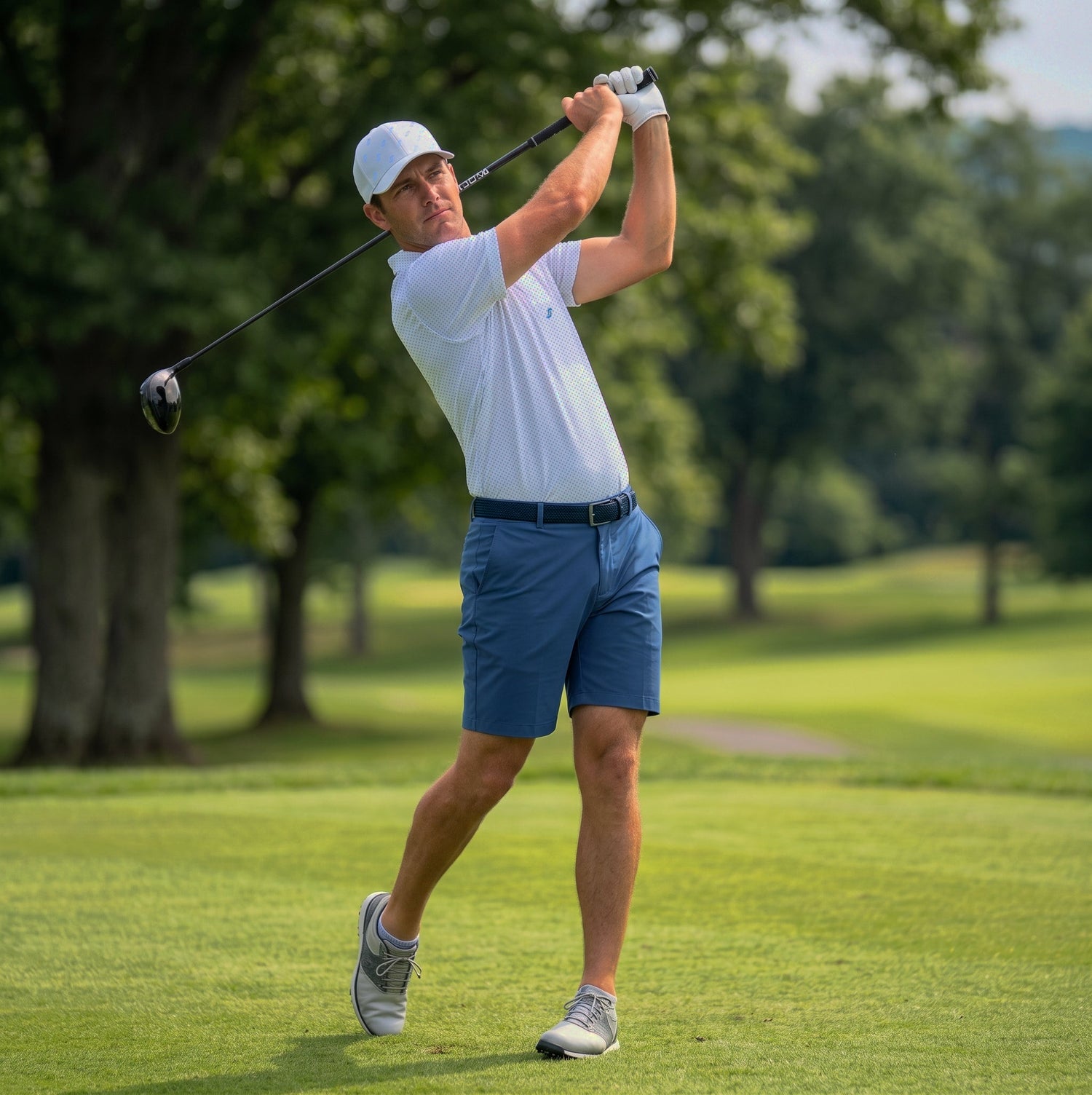 Male golfer wearing Cape Blue tradewinds short, navy executive belt, aquamarine matrix polo and white/cornflower legacy hat