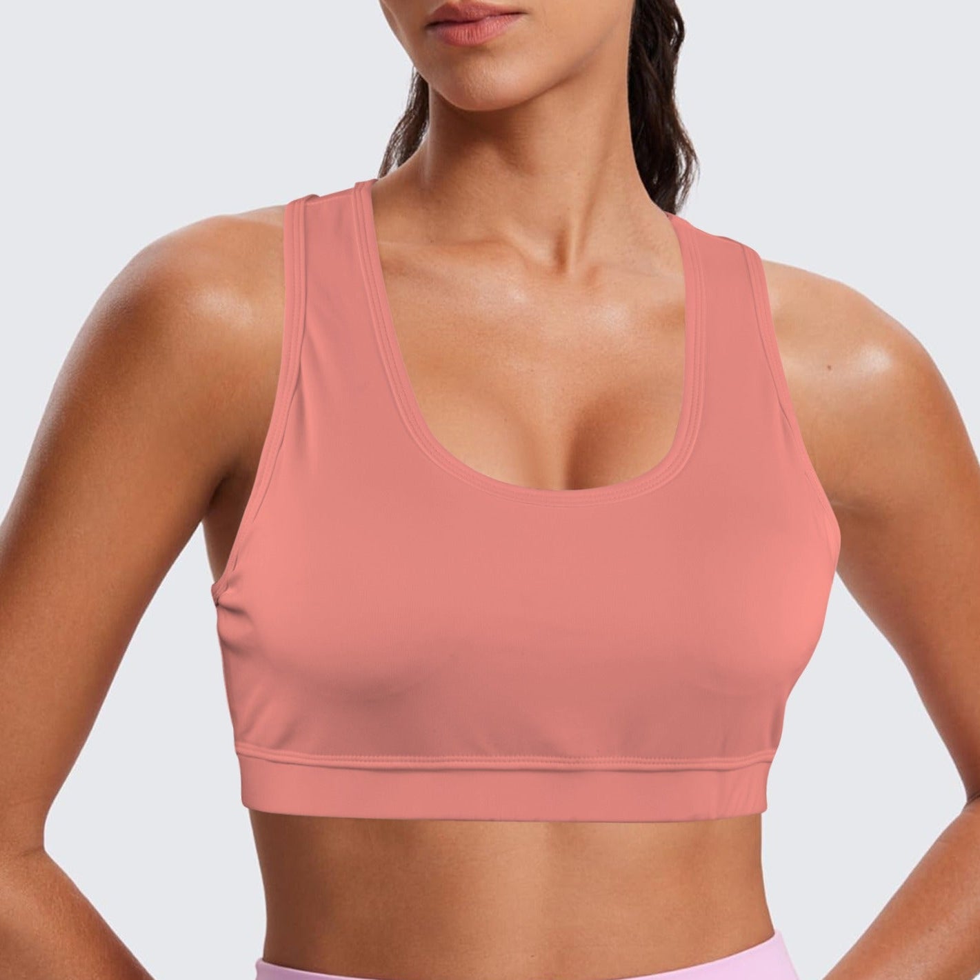 Person wearing a pink sports bra and pink leggings on a light gray background