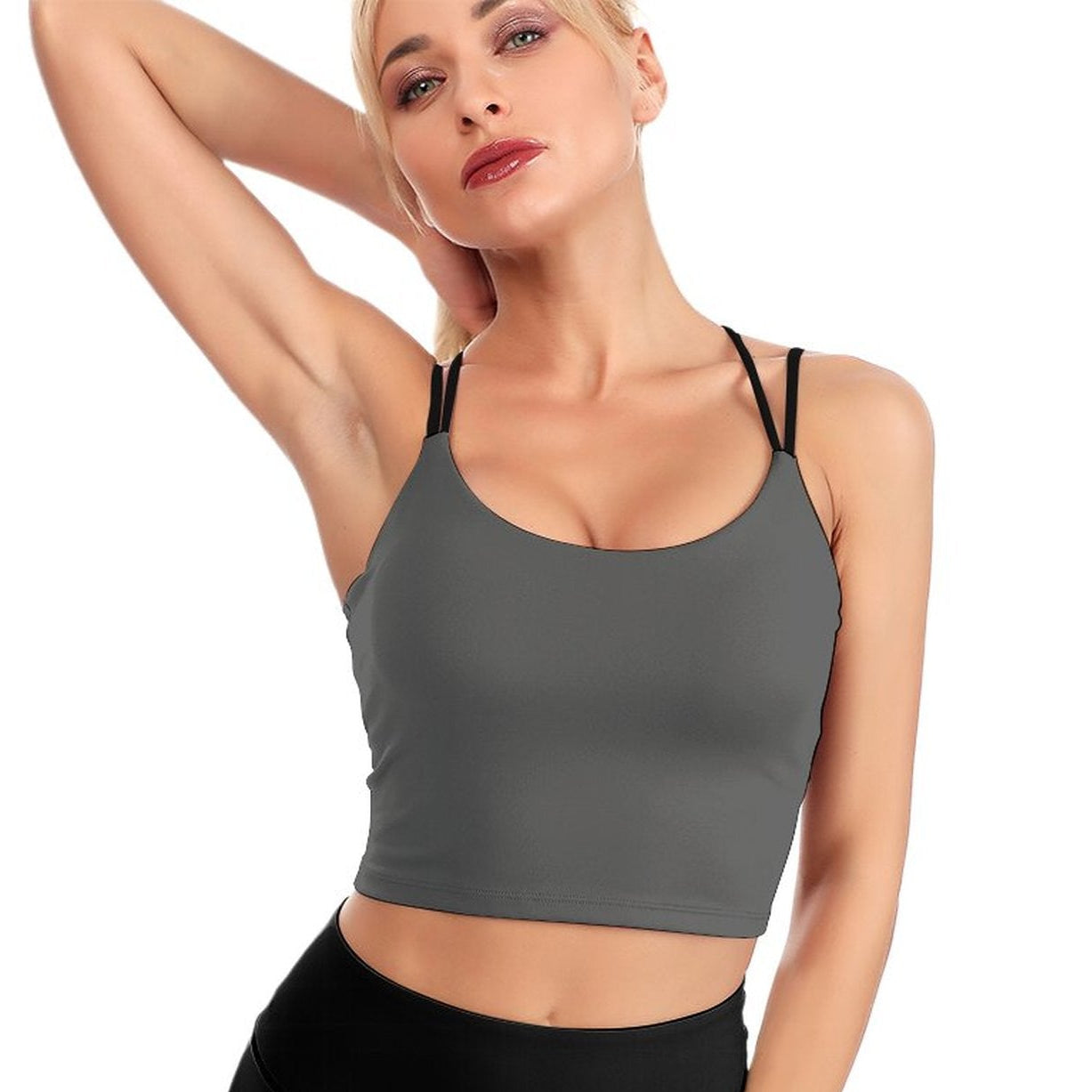 Woman wearing a gray sports bra and black leggings on a white background