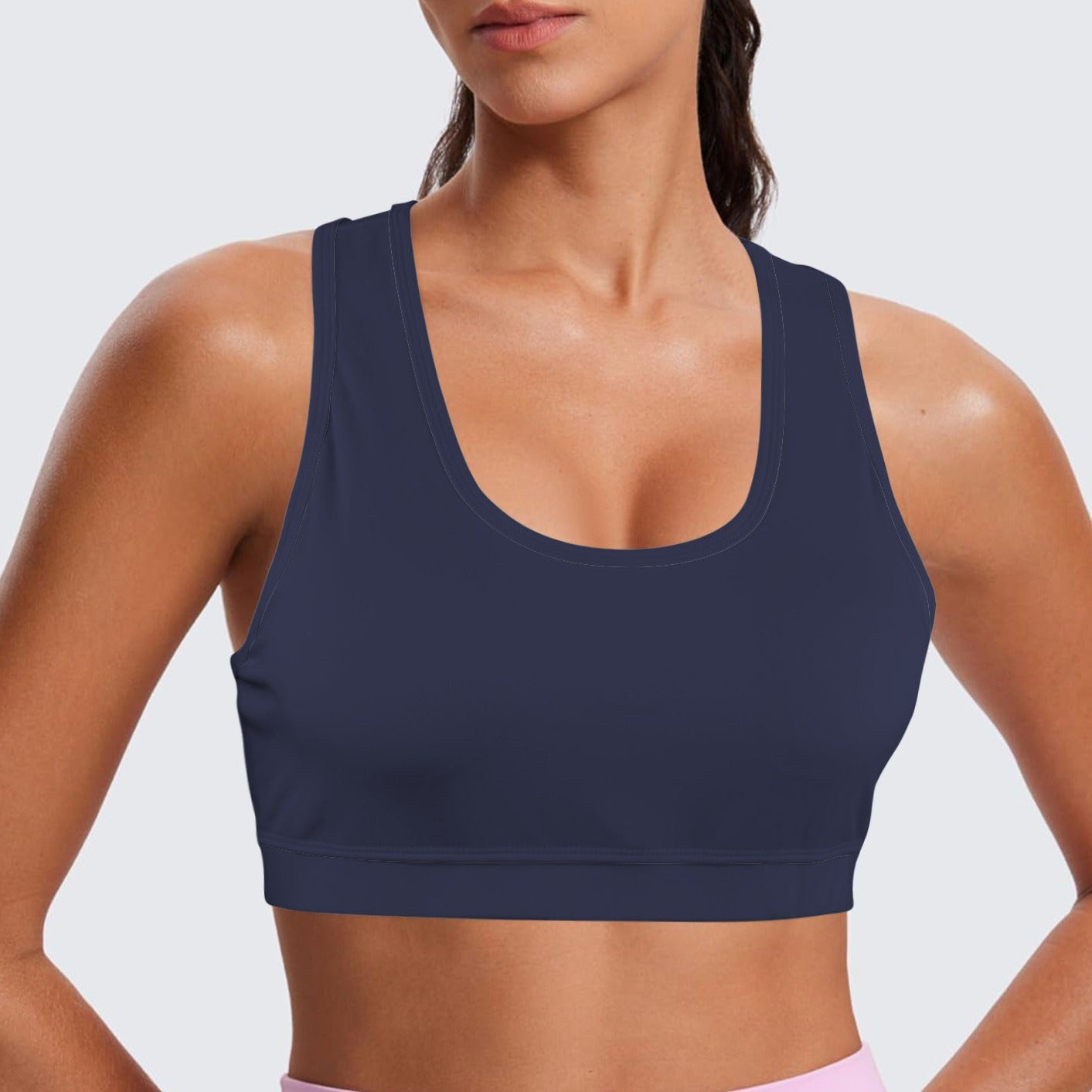Person wearing a navy blue sports bra and pink leggings on a light gray background