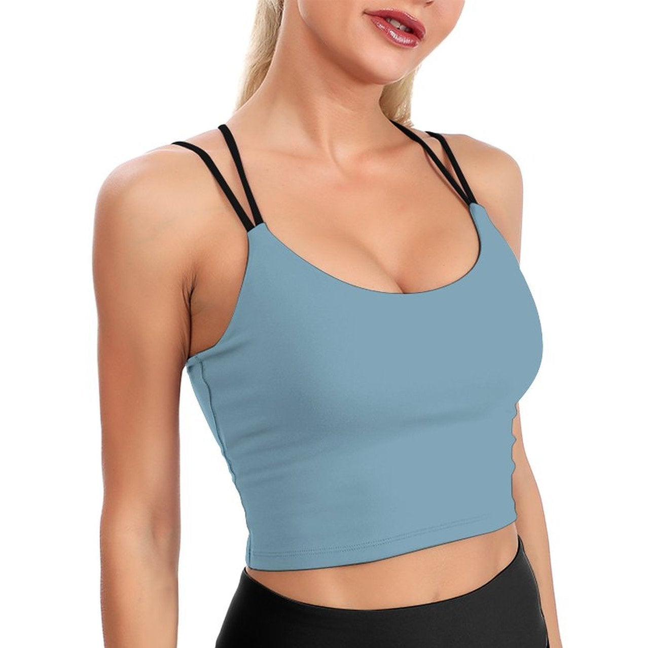 Woman wearing a light blue sports bra and black leggings on a white background
