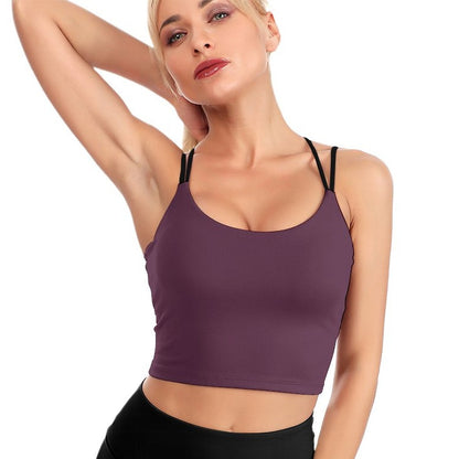 Woman wearing a purple sports bra and black leggings on a white background