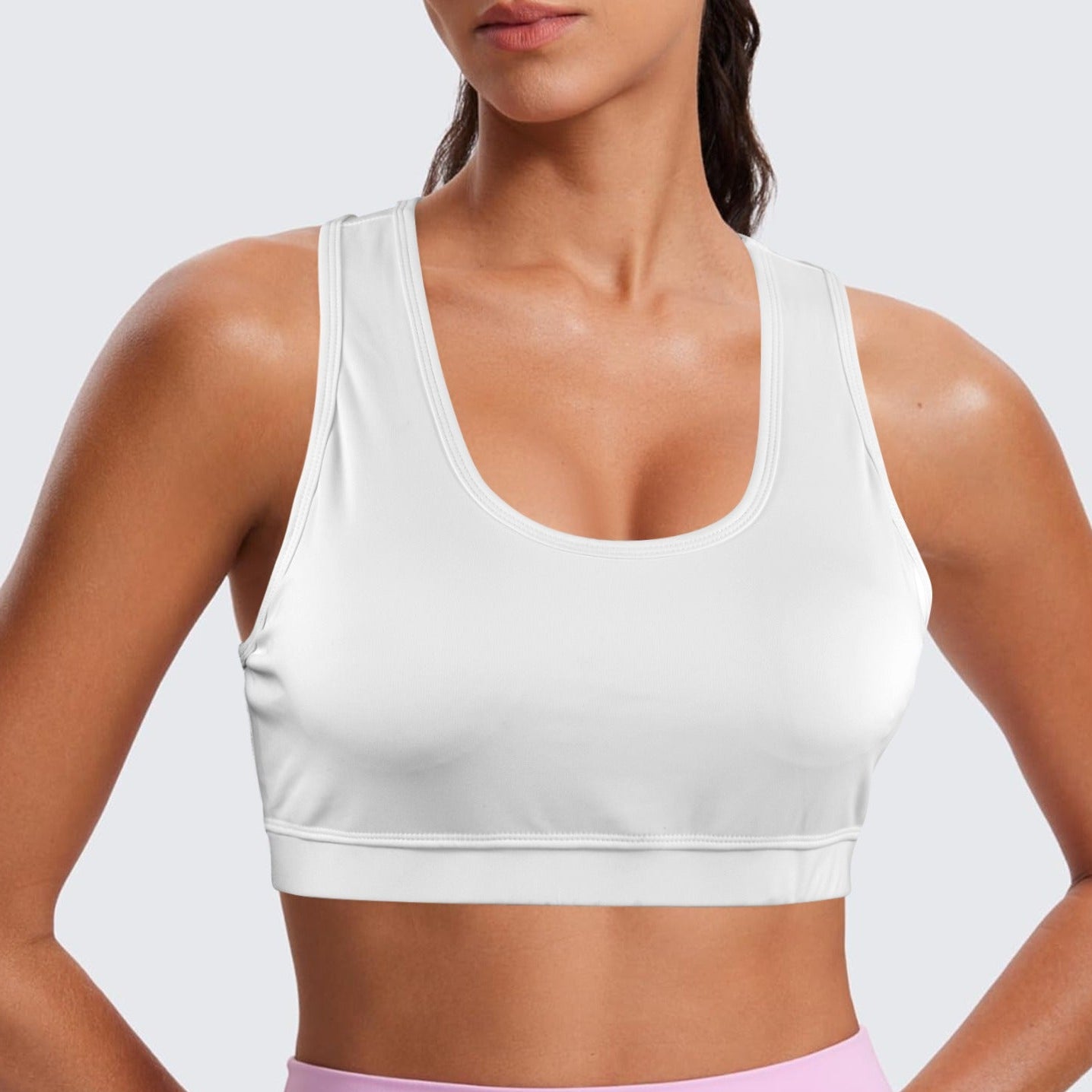 Person wearing a white sports bra and pink leggings on a light gray background