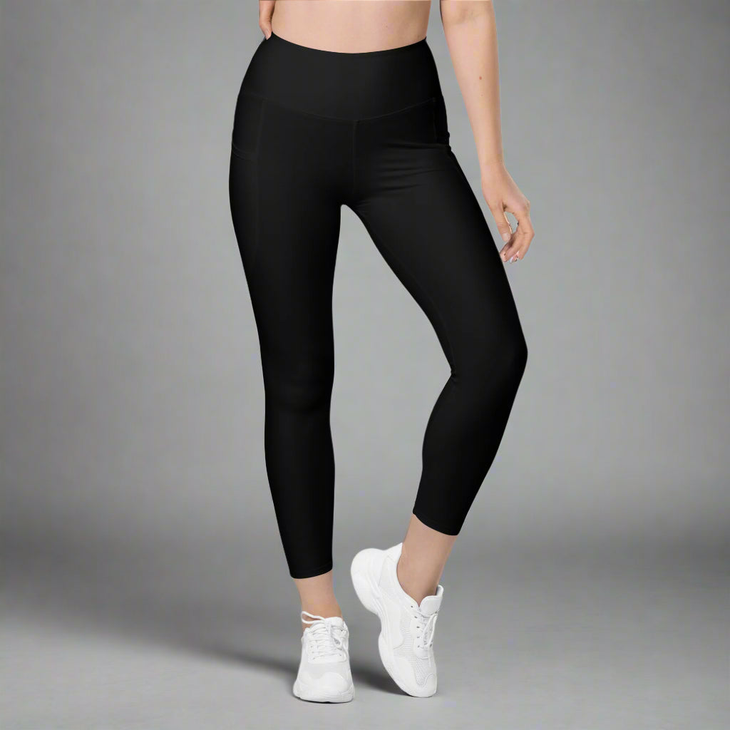 Person wearing black leggings and white sneakers on a gray background