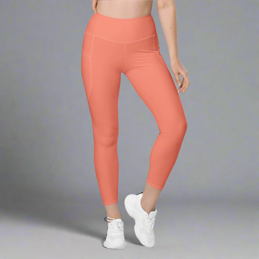 Coral leggings worn by a person on a gray background