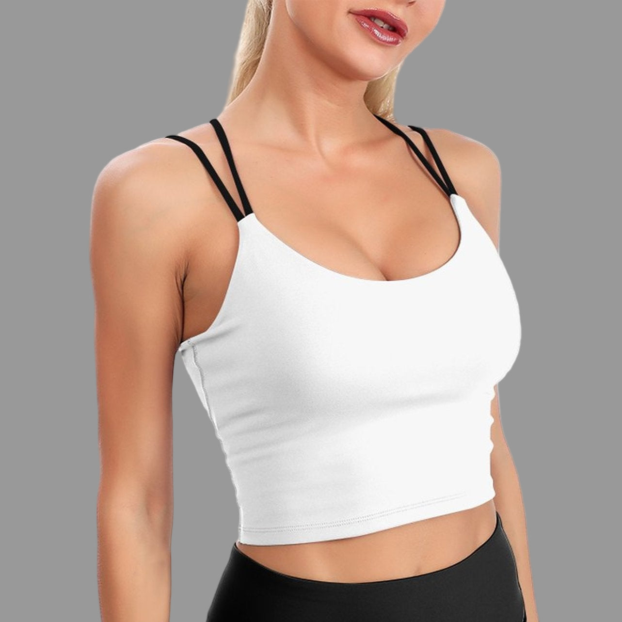 White crop top with thin black straps worn by a model on a white background