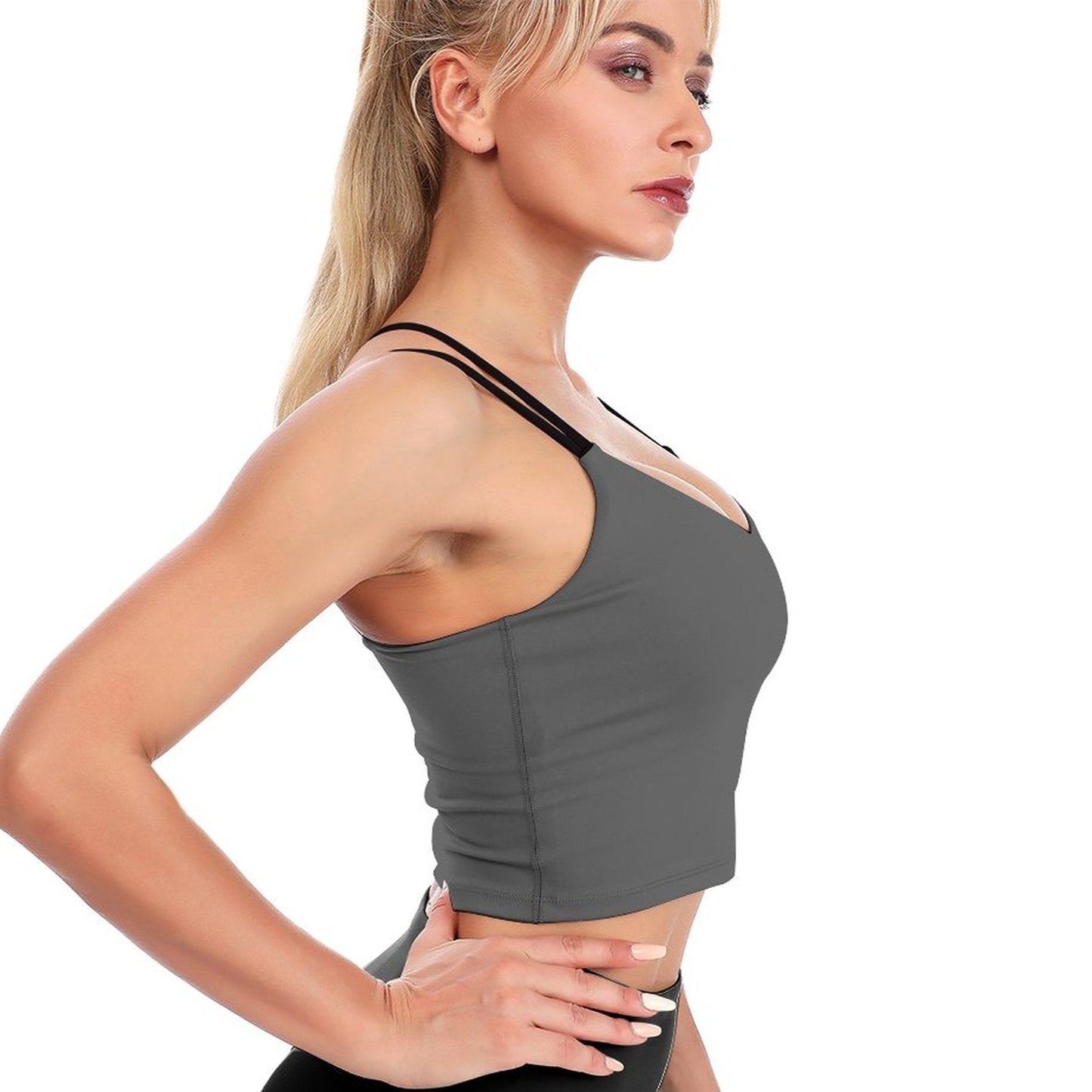 Woman wearing a gray sports bra and black leggings on a white background